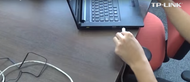 Pessoa conectando o cabo de internet num notebook